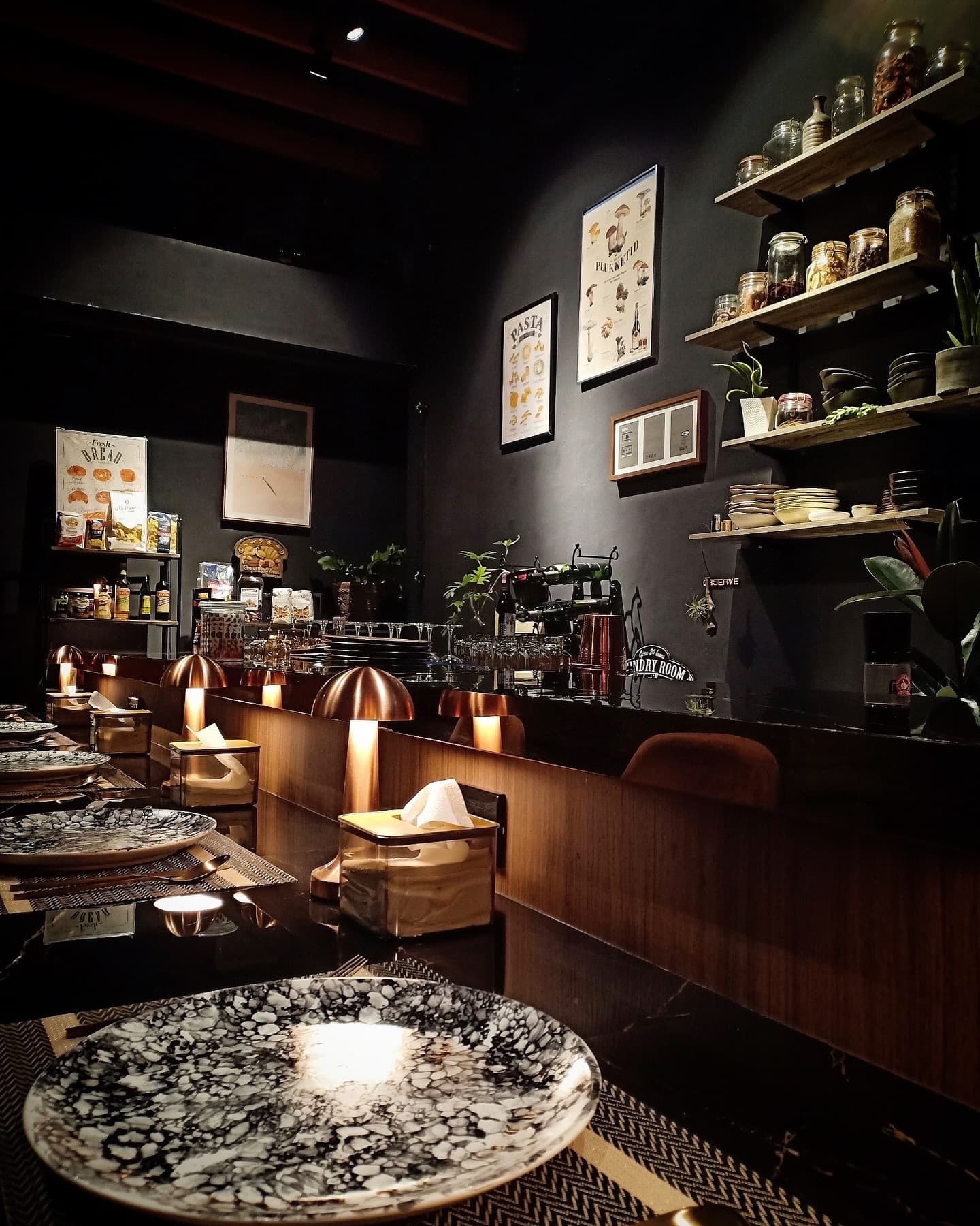 The intimate counter at Ob'serve glowing with copper lamps, vintage plates and shelves of jars before service