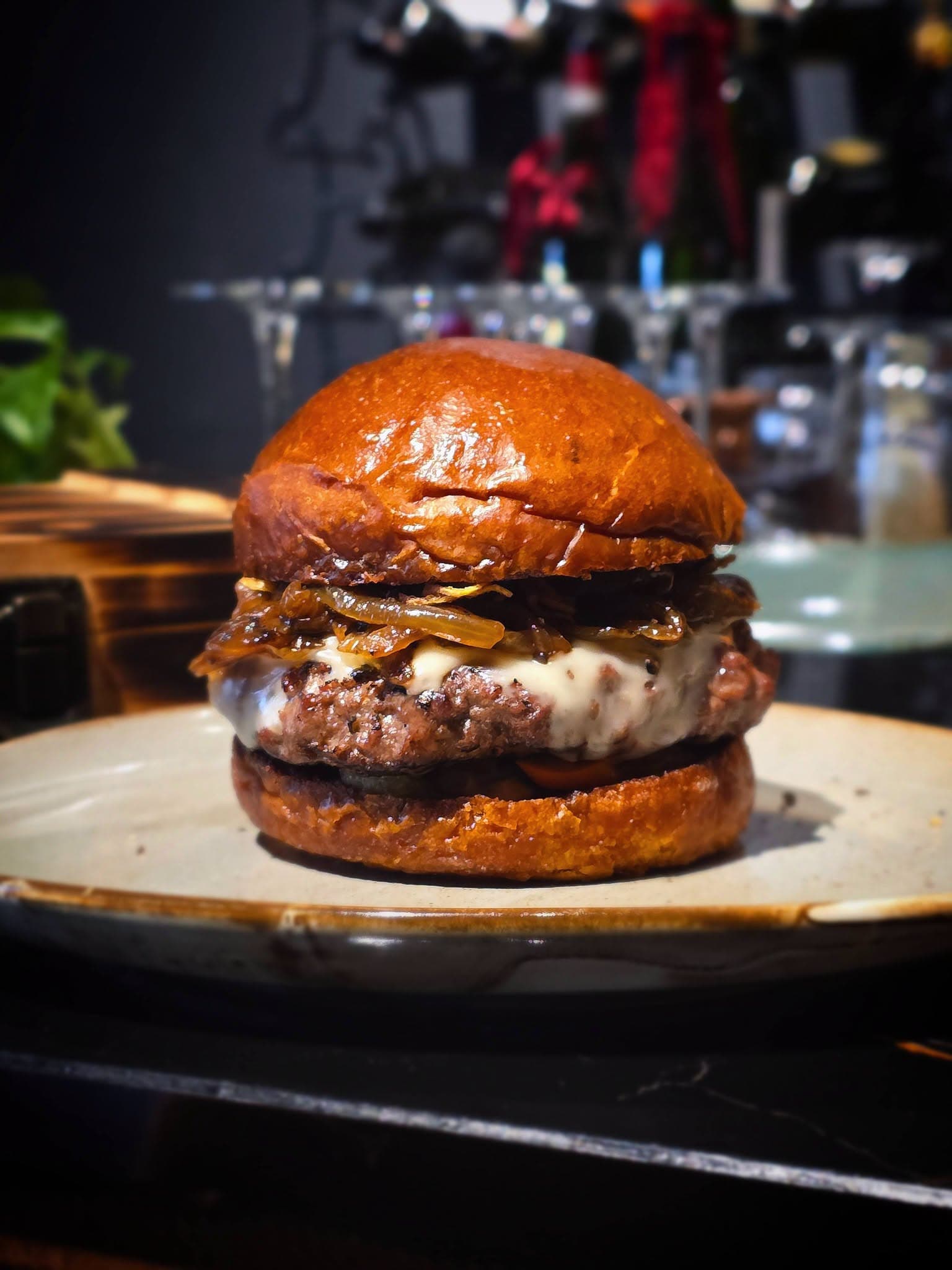 Ob'serve beef burger with melted cheese and caramelised onion on a glazed brioche bun at the counter